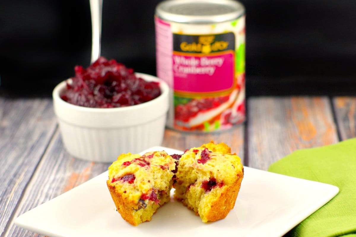 cranberry cornbread muffin spilt in half with cranberry sauce and can in the background