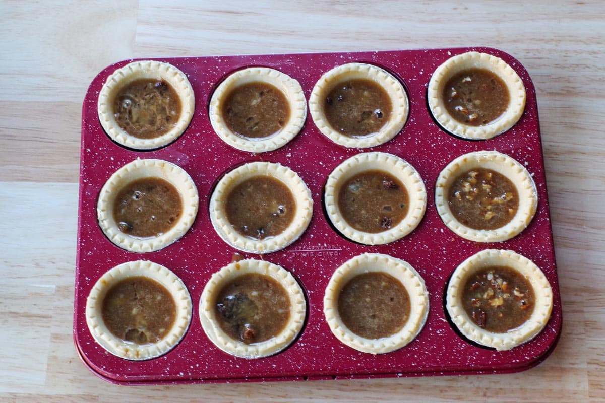 tart shells with filling in red speckled muffin tin