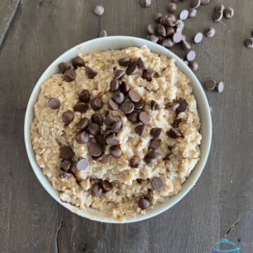 overhead view of chocolate chip cookie dough overnight oatmeal in a white bowl on wooden surface