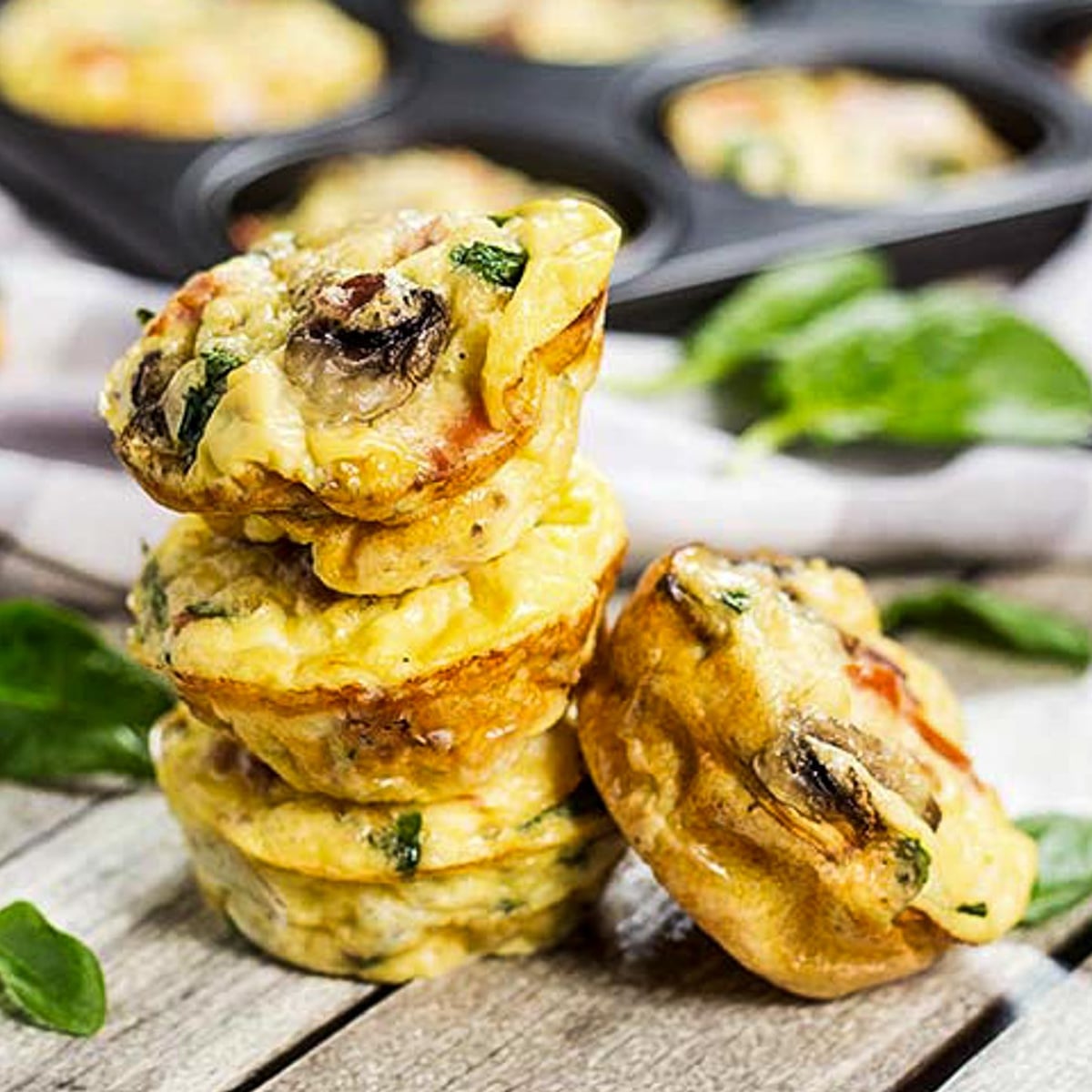 3 muffin tin omelettes stacked on top of each other, with one leaning against the tower of muffins