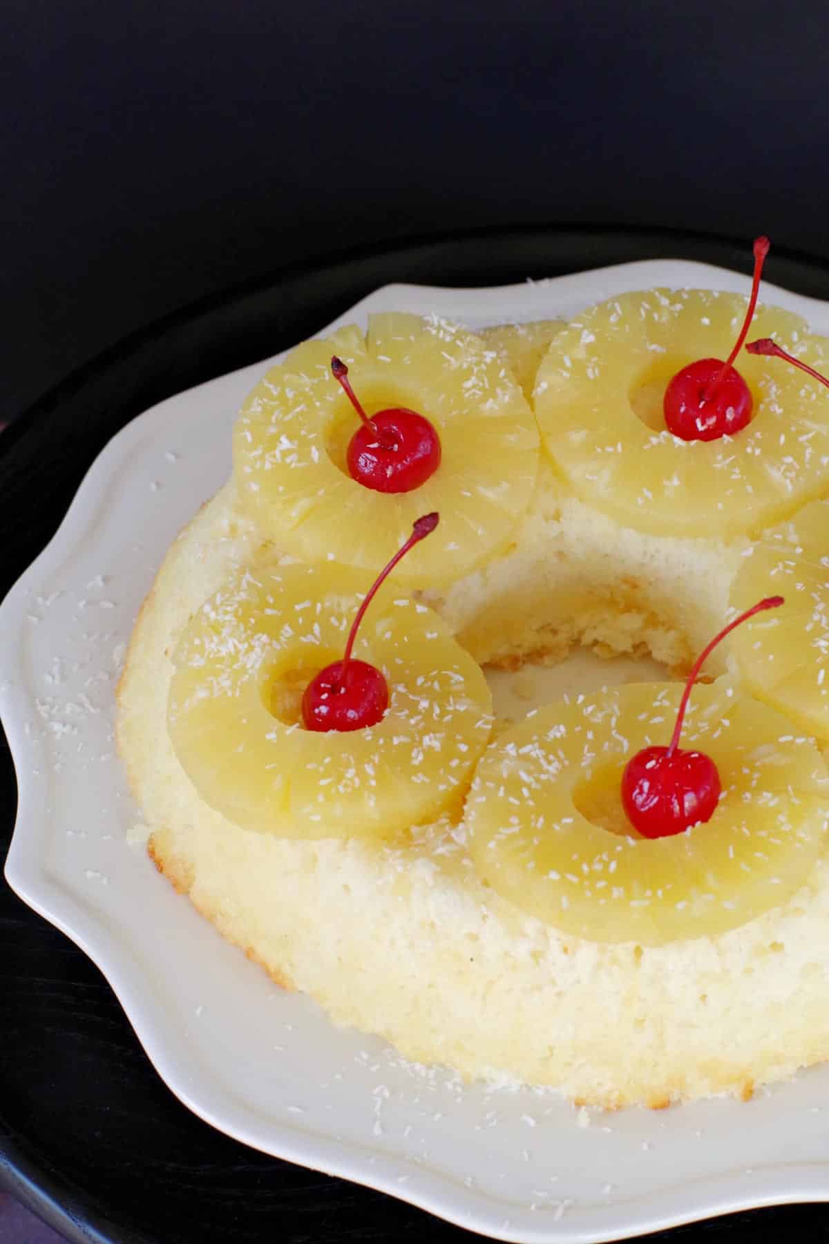 ww pineapple (pina colada) cake garnished with pineapple and cherries on a white plate