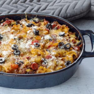 healthy pizza casserole in a blue casserole dish with grey oven mitts in the background