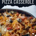 spoonful of pizza casserole being held up on a dark wooden spoon over casserole dish