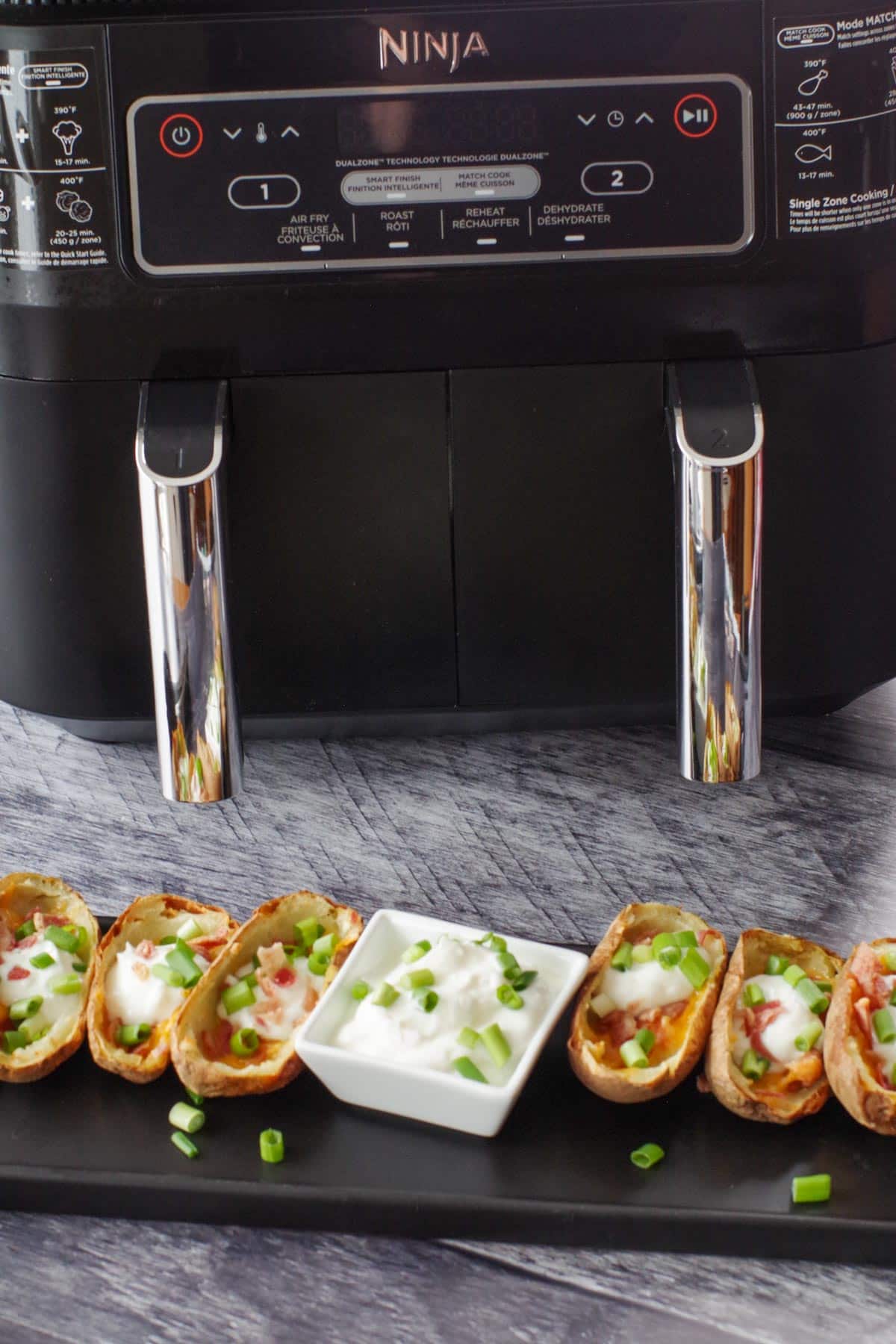 potato skins on a black tray in front of air fryer
