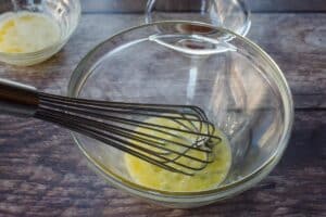 egg being whisked in a glass bowl