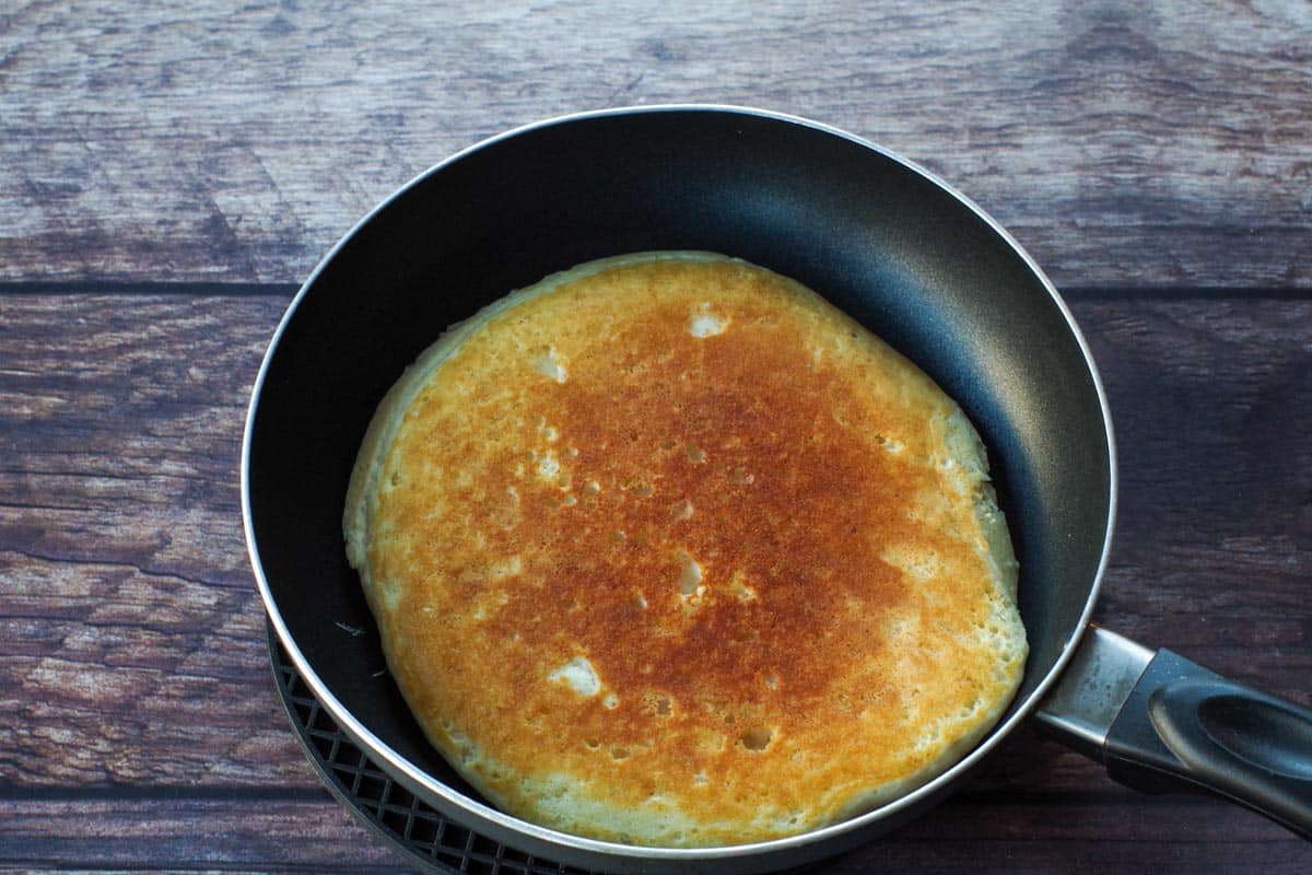 pancake cooked on one side and flipped in the frying pan