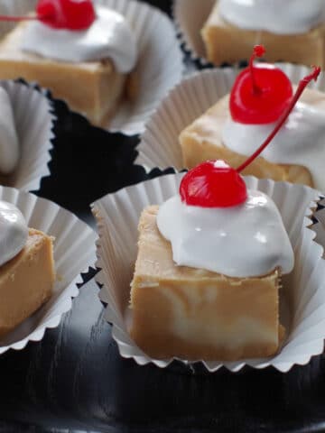 pieces of root beer float fudge on cupcake liners, on a black tray