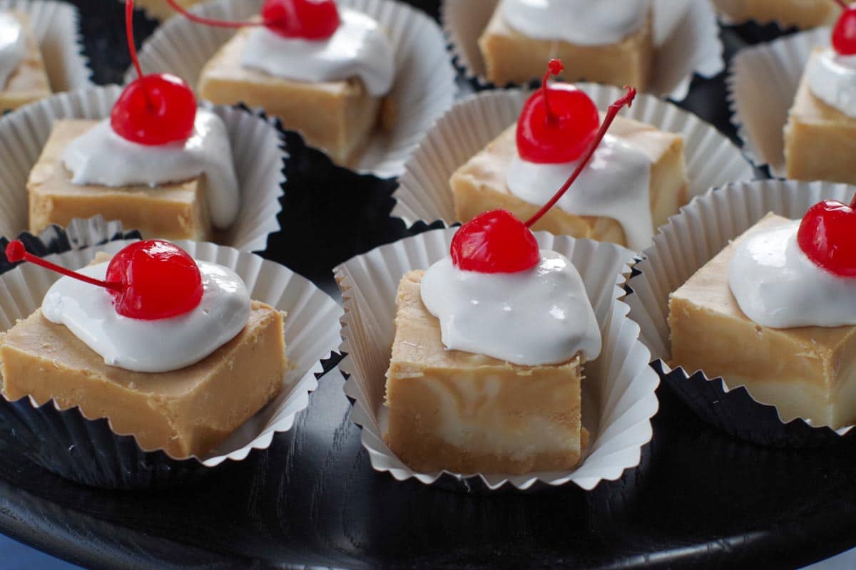pieces of root beer float fudge on cupcake liners, on a black tray