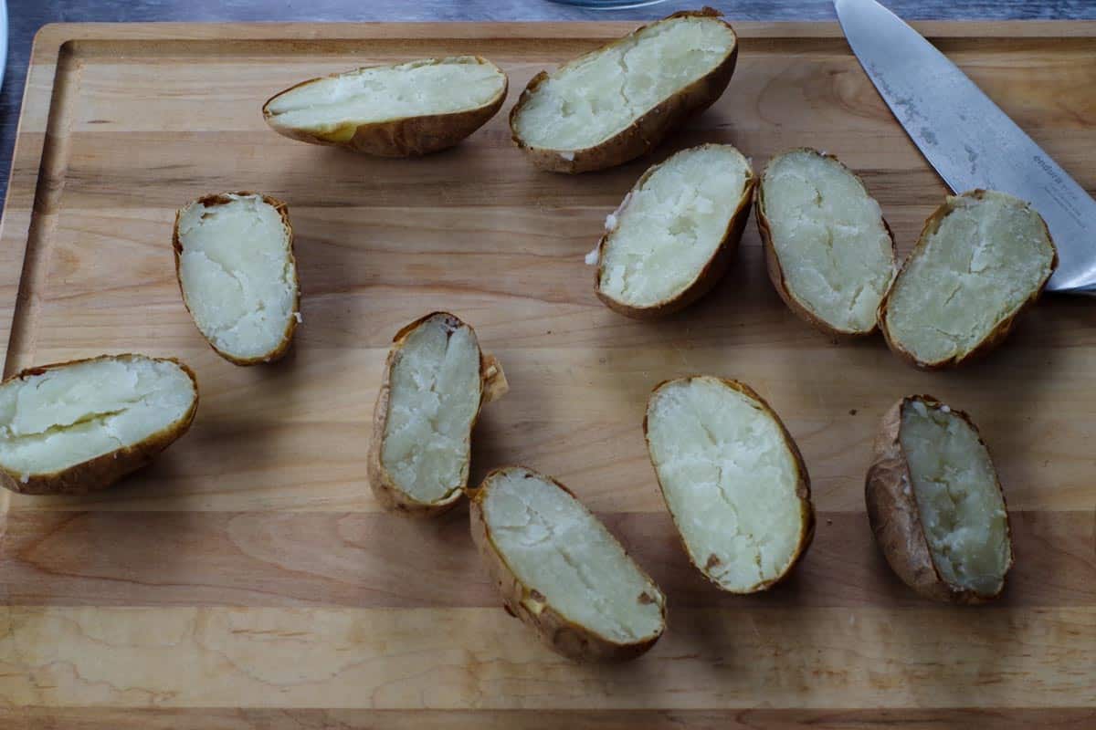 baked potatoes cut in half on a wooden cutting board