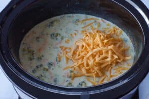 cheese being added to slow cooker broccoli soup