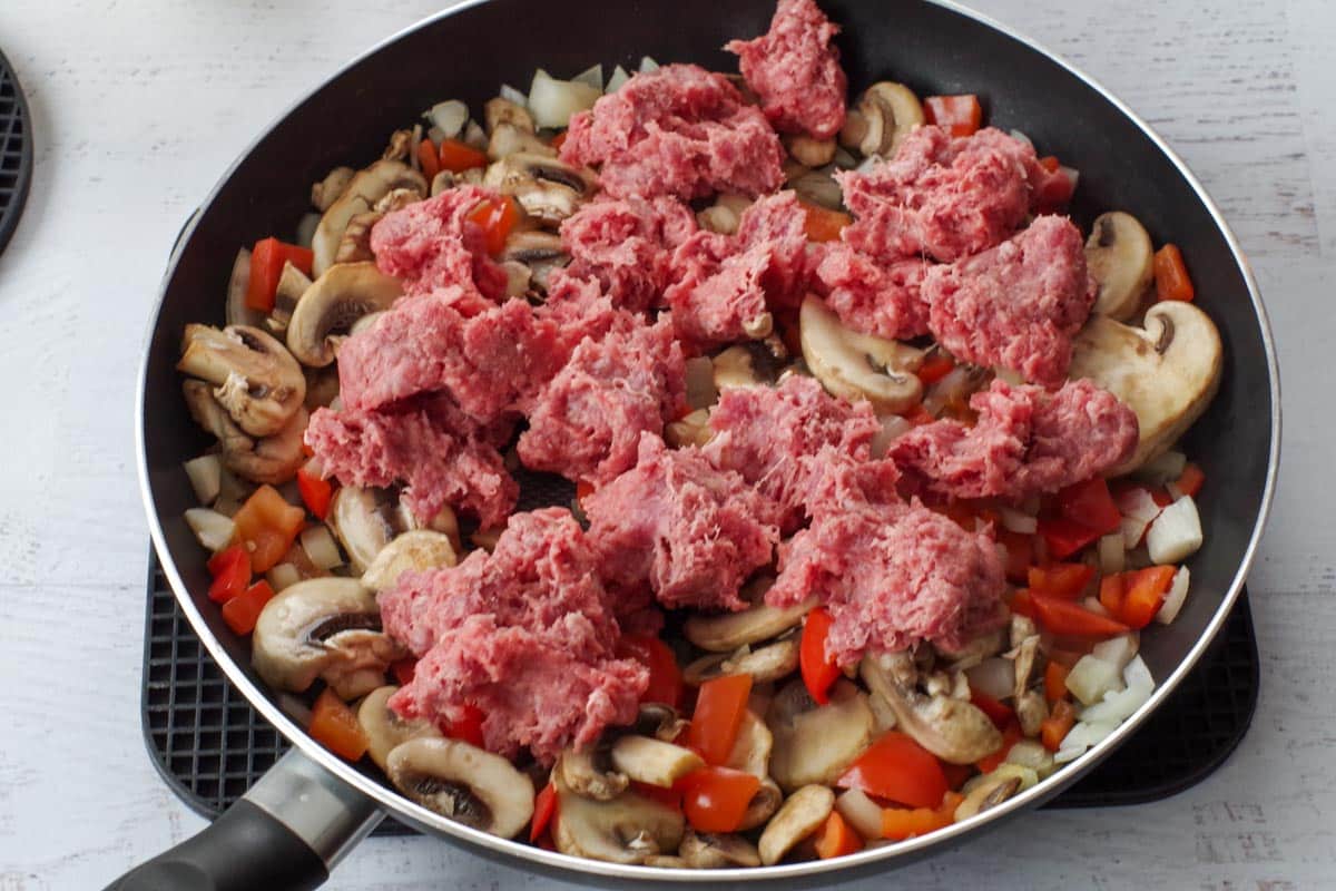 ground beef added to vegetable mixture in skillet