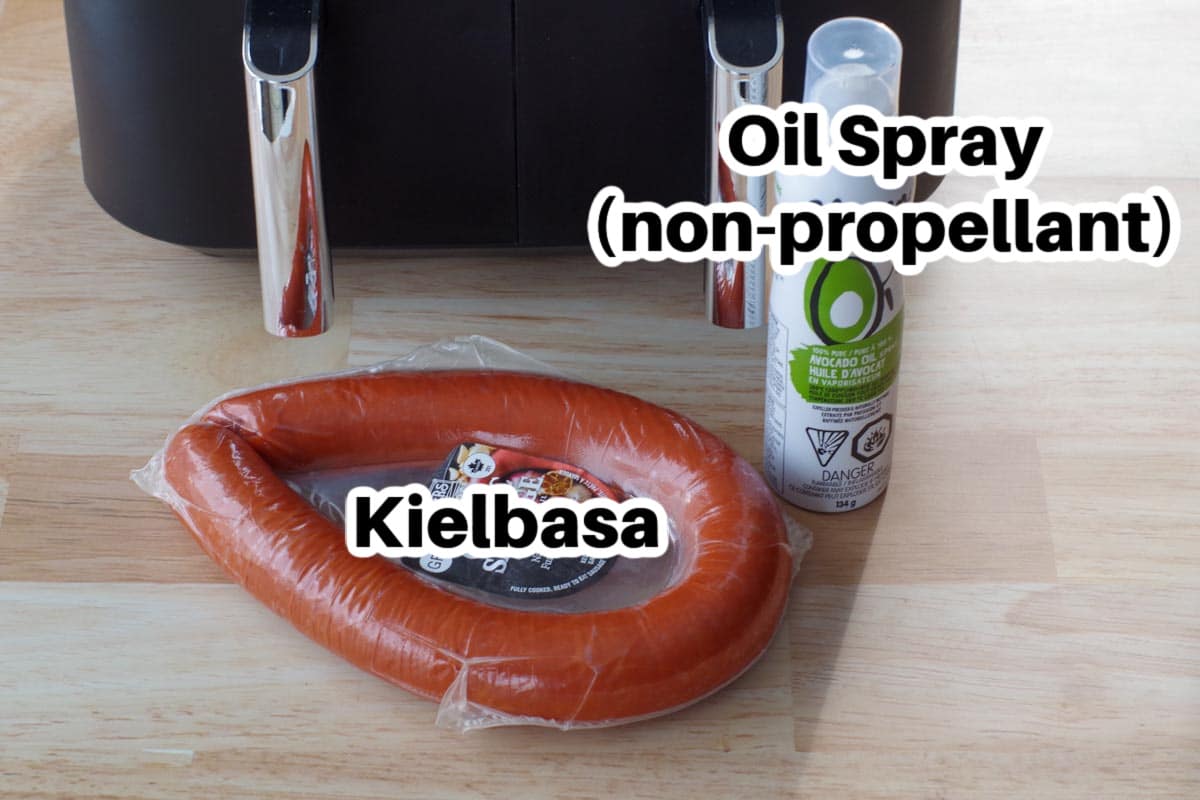 kielbasa and spray oil on counter surface with air fryer in the background