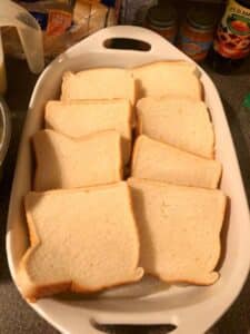 slices of bread, overlapping placed in white casserole dish