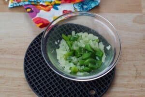 onions and green peppers cooked in a glass bowl on black trivet