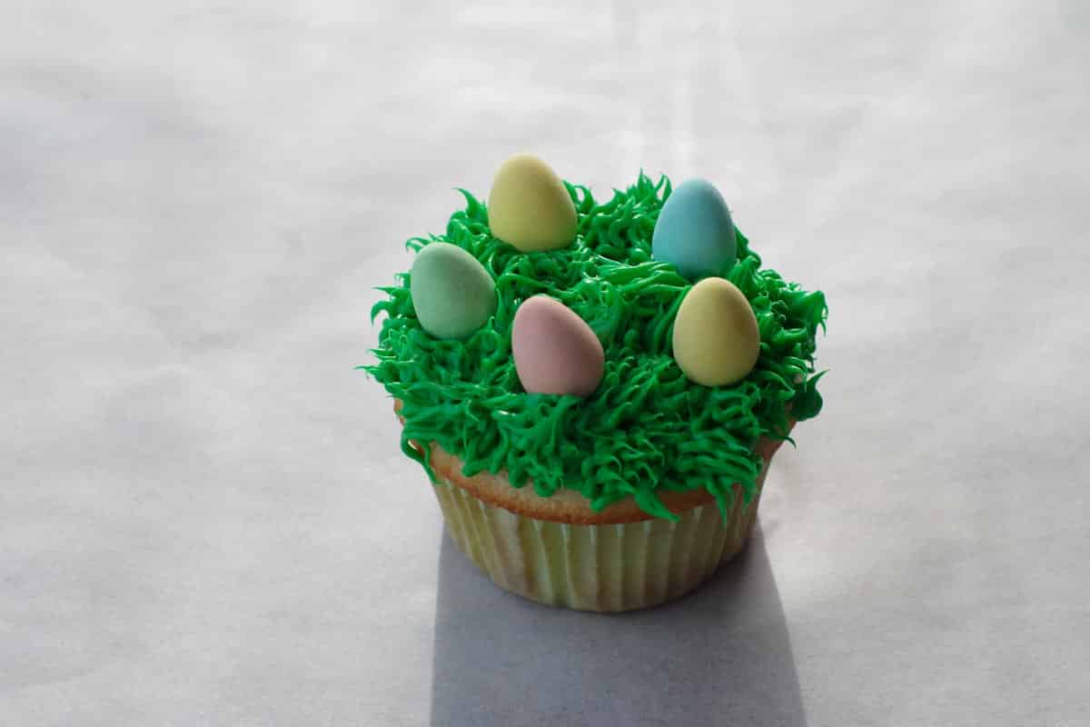 5 mini eggs added to top of grass frosting covered cupcake