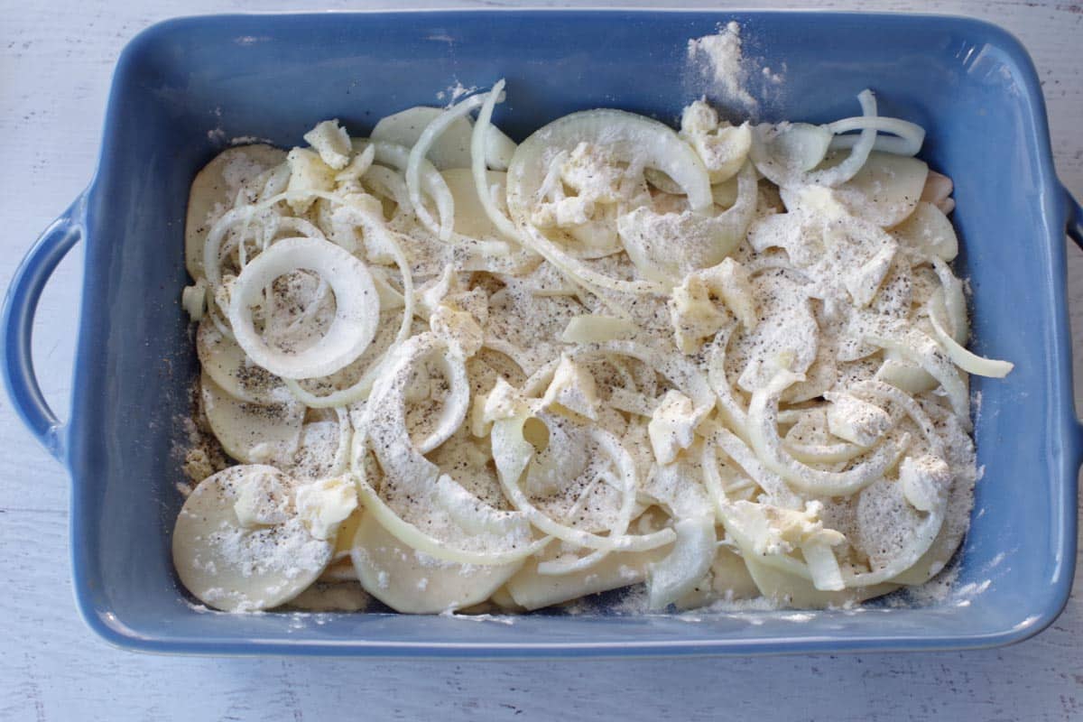 butter, flour and salt and pepper on top of first layer of onions and potatoes in blue casserole dish