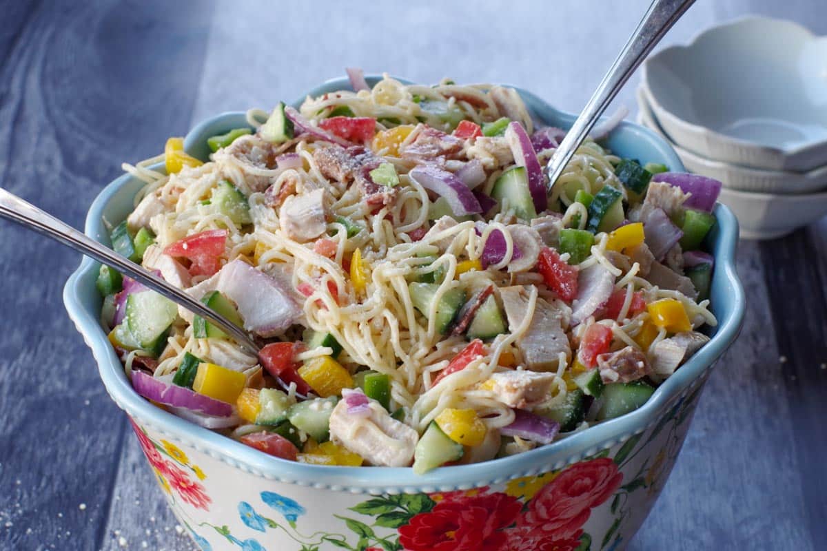 chicken bacon ranch pasta salad in a flowered bowl with white bowls in the bakground