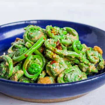 fiddlehead salad with sesame dressing in a blue bowl