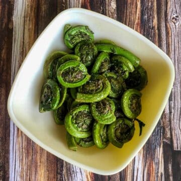 Fiddleheads with lemon and butter in a white bowl