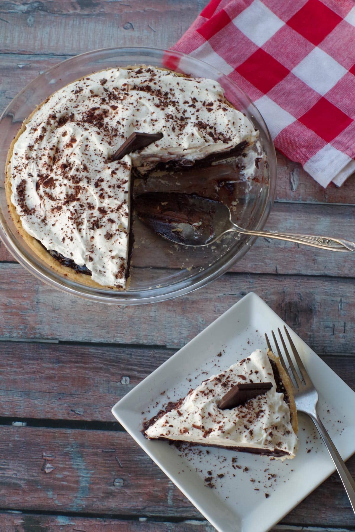 top view of old fashioned chocolate pie, with piece of white plate and pie pan with more pie