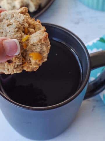 rhubarb cookie being dipped into a black mug of coffee