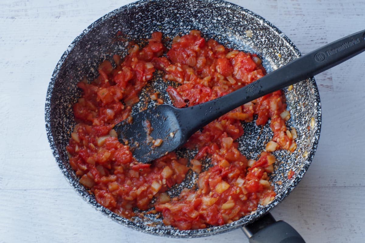 spices and tomato paste mixed in and cooked, with black spatula
