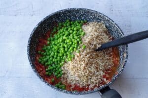 peas and rice added to tomato mixture in pan