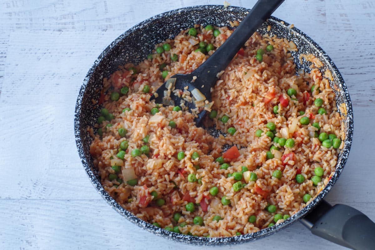 cooked spanish brown rice, with liquid absorbed, in skillet with black spatula