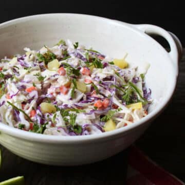 tropical pineapple coconut coleslaw in a sage green and white bowl