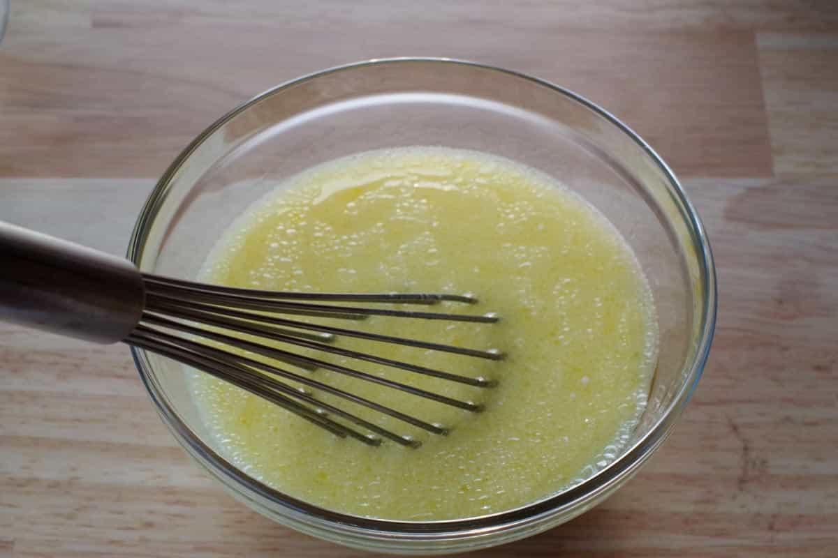 milk, egg yolks and vegetable oil in a glass bowl, being whisked together