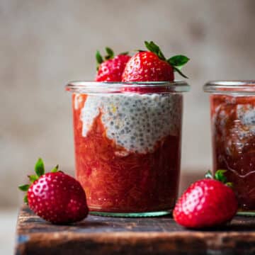 rhubarb chia pudding in glasses with strawberries on a wood surface