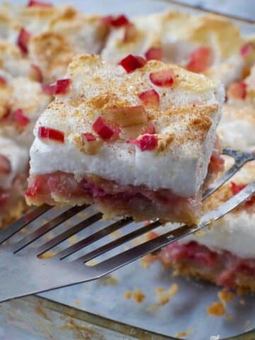 a piece of rhubarb torte being held up over a pan of more rhubarb torte