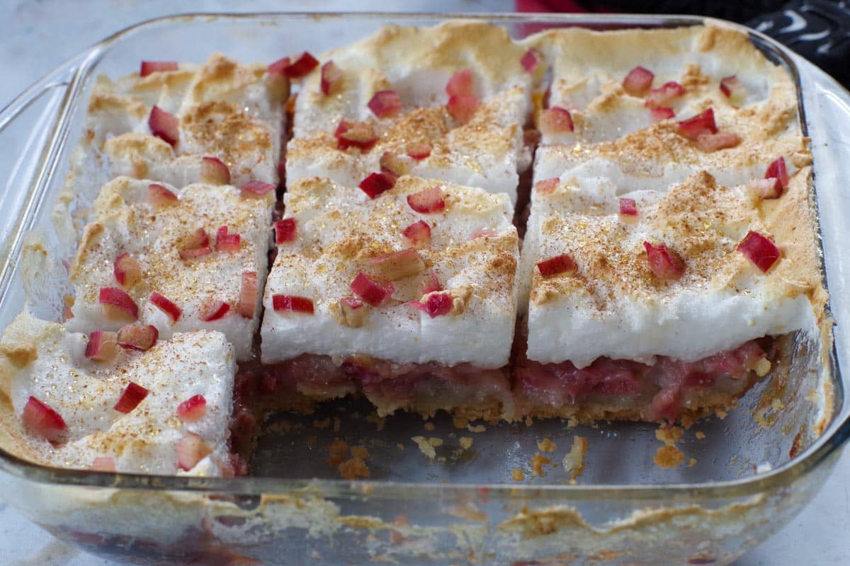 rhubarb torte in a glass pan with 2 pieces missing
