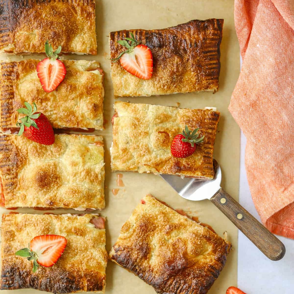 strawberry rhubarb puff pastry cut into pieces with strawberries on top of some pieces