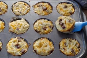 brunch bites in muffin tin, with one being lifted out with a blue spatula