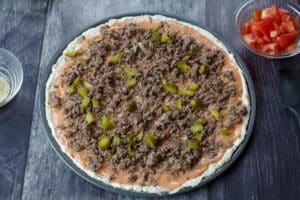 big mac pizza with sauce, cooked ground beef with onion and half the chopped pickles
