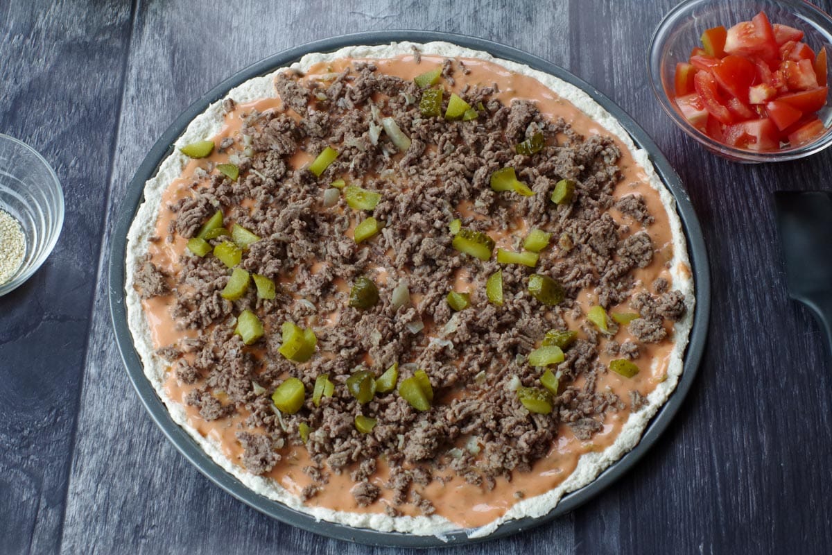 big mac pizza with sauce, cooked ground beef with onion and half the chopped pickles
