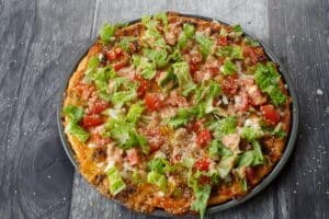 lettuce tomatoes, onions, pickles and sesame seeds added to big mac pizza