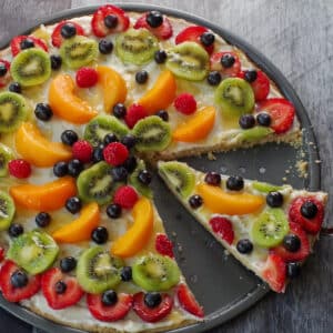 fruit pizza with a slice being lifted out