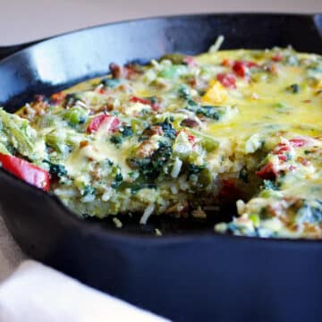 pasta frittata with vegetables and sausages in a black frying pan
