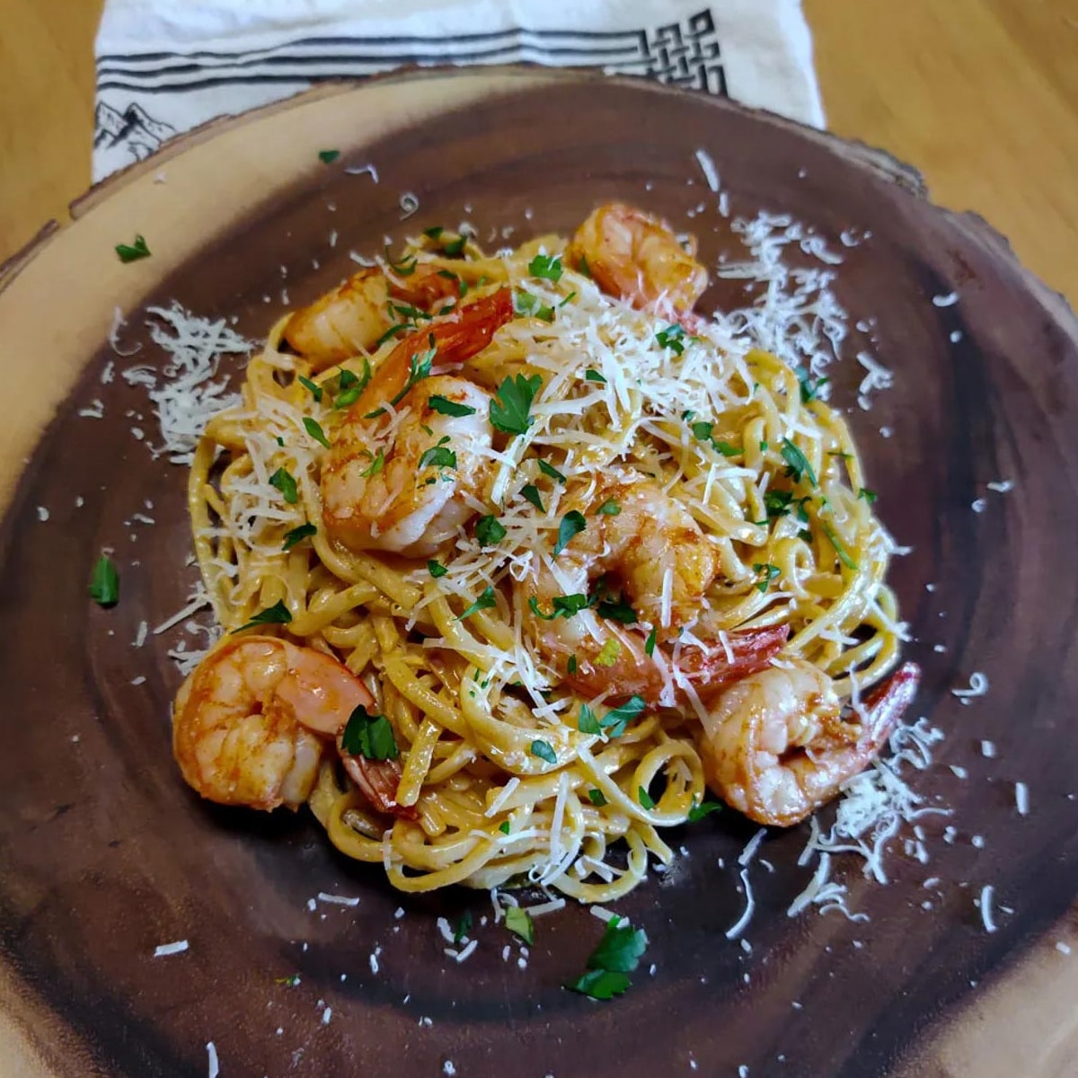 spicy shrimp pasta on a brown wooden platter