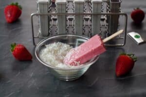 strawberry greek yogurt popsicle in a bowl with shredded coconut