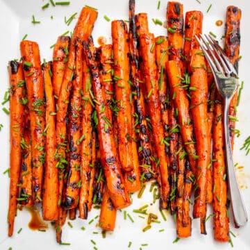 grilled balsamic glazed carrots on a white surface, with a fork