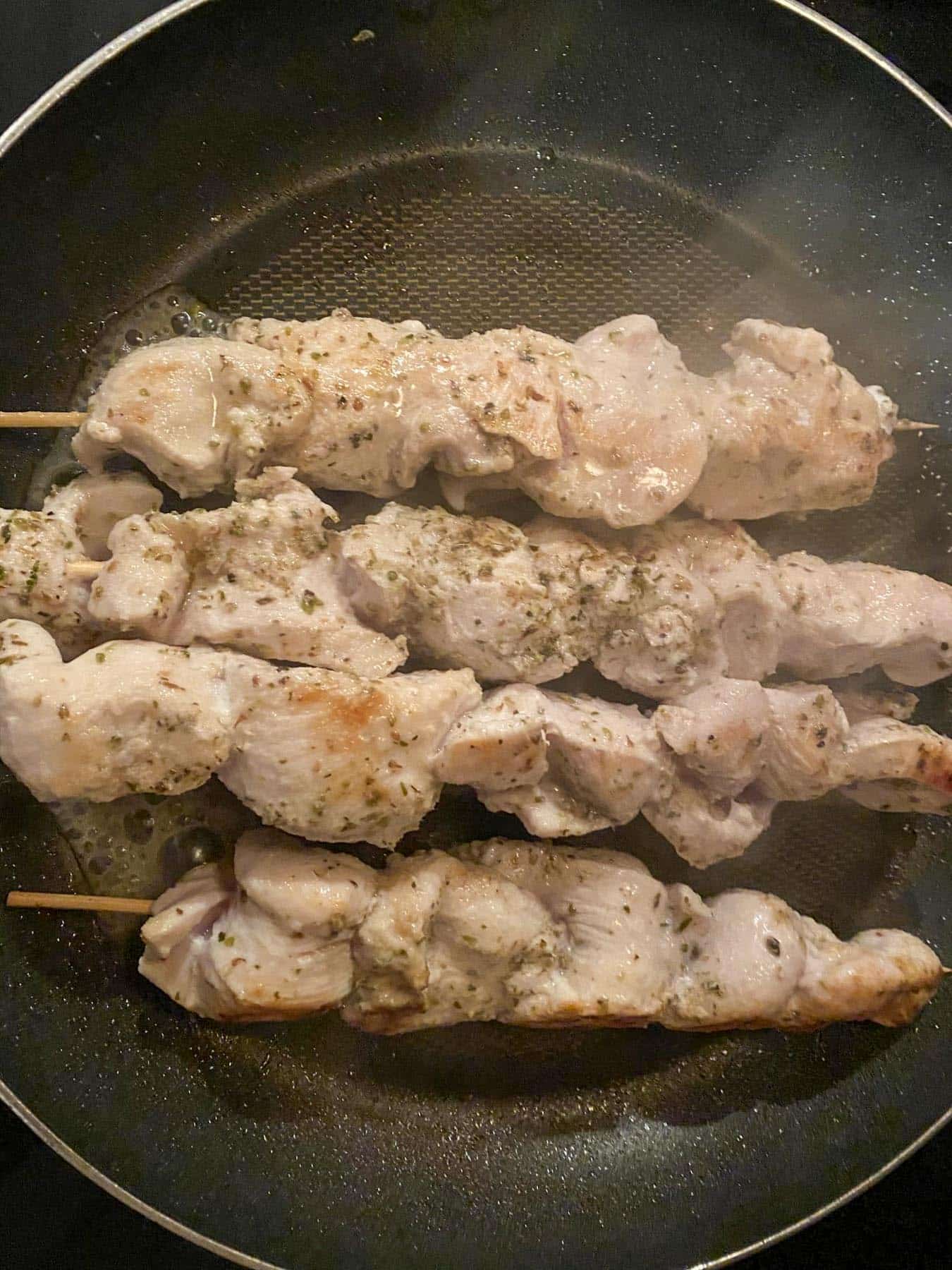 cooked chicken souvlaki skewers in a frying pan