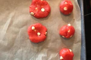 strawberry milkshake cookie dough rolled into balls and flattened on a parchment lined cookie sheet