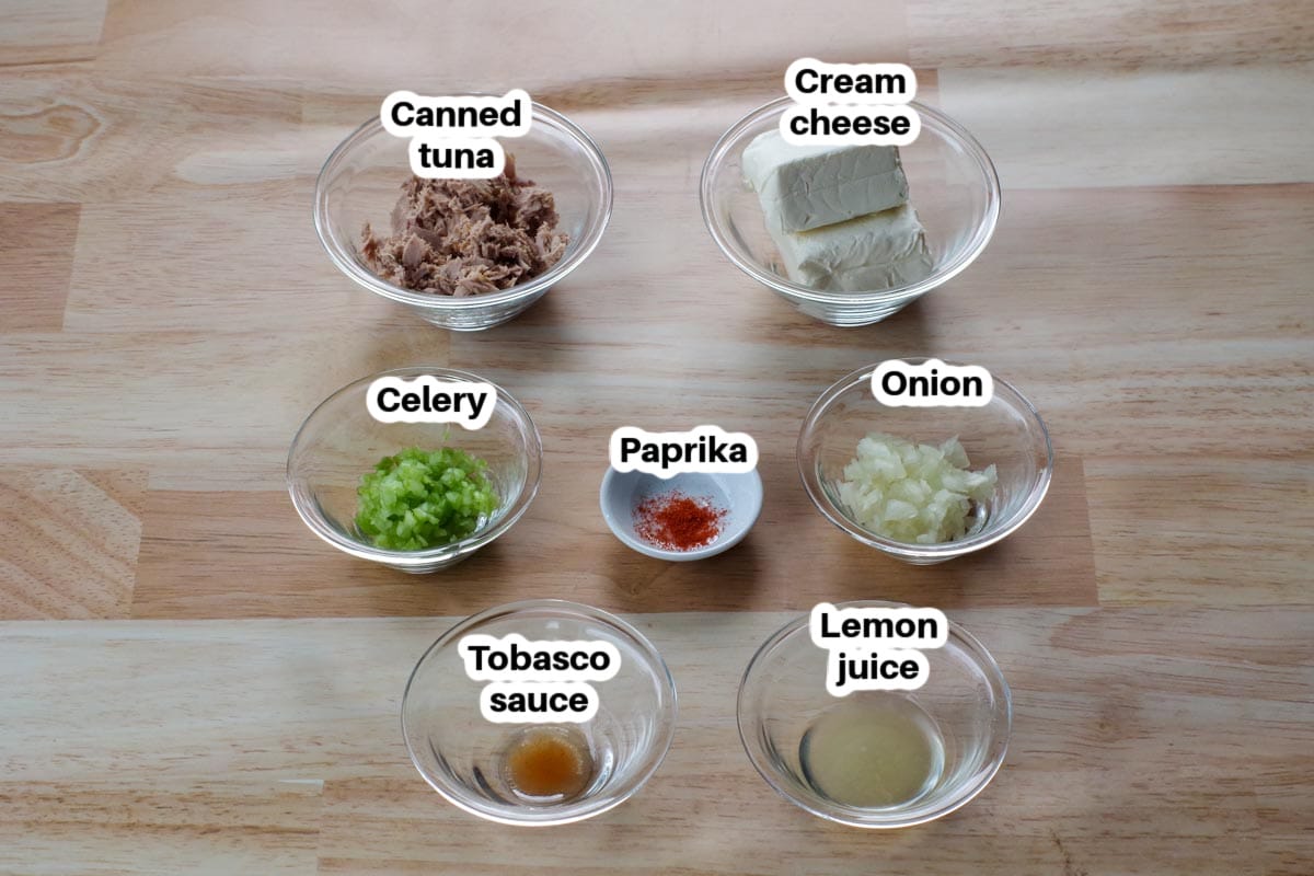 tuna dip ingredients in glass bowls, labelled, on a faux wooden surface