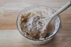 tuna dip mixed together in a glass bowl with a wooden spoon