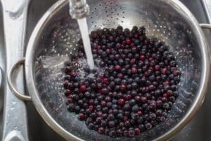 berries in colander with water running