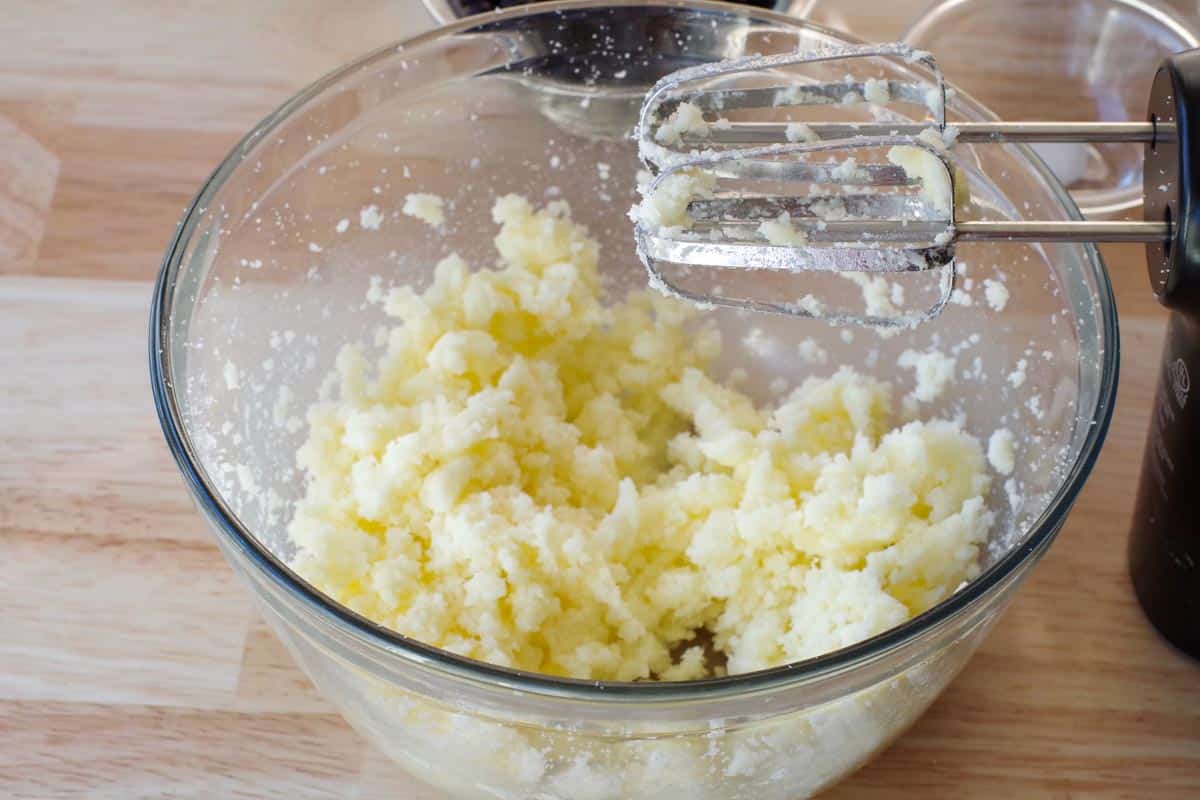 butter and sugar beaten together in glass mixing bowl with beaters over bowl