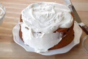 cake being covered with whipped cream frosting